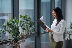 Pregnant businesswoman looking at documents in office lobby