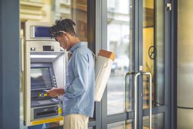 Young man uses ATM to conduct a bank transaction