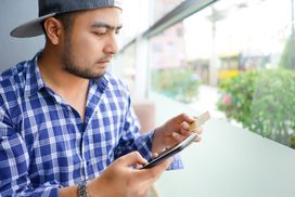 Man looking at credit card and typing on smartphone