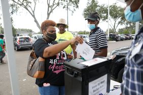 People placing voting ballot in collection box