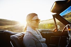Mature woman wearing sunglasses driving at sunset