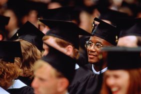 Graduates at graduation ceremony (focus on young man in glasses)