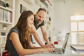 dad and daughter sitting in office working on something on computer