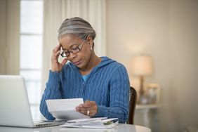 A woman looking concerned as she reviews documents about her 401(k) plan.