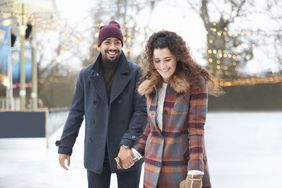 Couple on ice rink holding hands smiling
