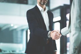Man in a suit shaking hands with another person in an office
