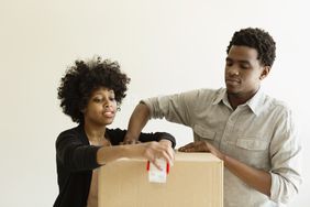 Black couple taping up moving boxes