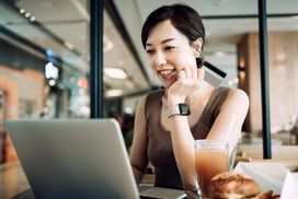Beautiful smiling young Asian woman having meal in a cafe, shopping online with laptop and making mobile payment with credit card on hand