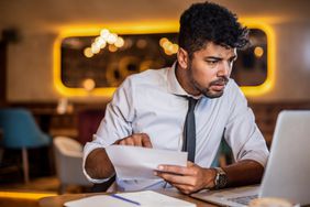 Entrepreneur looking at laptop to review paperwork