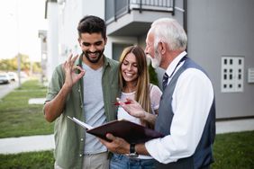 Happy couple examining documents with agent to sell house