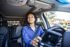 Young woman ride share driver, driving an older male customer