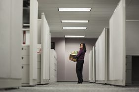 Woman leaving office with a box of her things after her job was terminated
