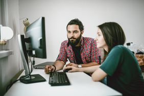 Young freelancing couple looks at computer in home office