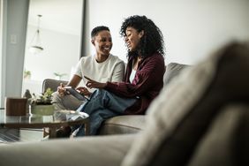 A couple looks at a tablet while sitting on a couch