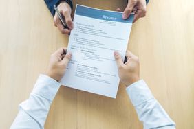 Cropped Hands Of Business People Holding Resume On Table In Office