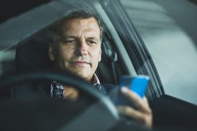 Man in a car looking at his phone