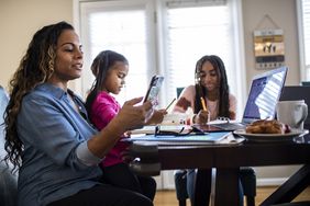 Woman on the computer with her daughters doing schoolwork at the table