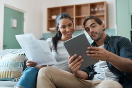 Shot of a young couple doing paperwork while using a digital tablet at home