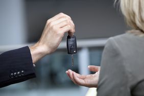 Salesman handing woman car keys in automobile showroom