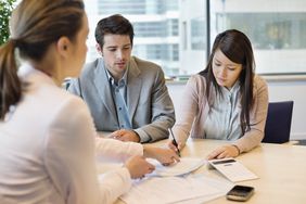 Young couple in office signing documents with business executive