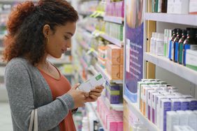 woman standing in pharmacy aisle looking at beauty products