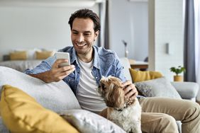 A man and his dog look at a phone. 