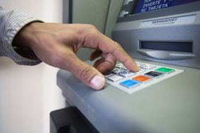 Close-up of person's hand pressing buttons on an ATM