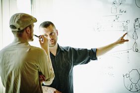 Two engineers discussing project design in office