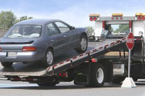 A repossessed car being loaded onto a flat-bed tow truck.