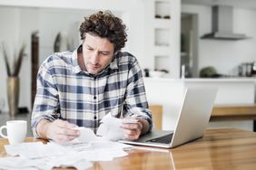 Serious man paying bills online at home