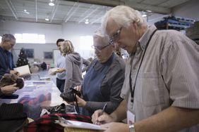 Senior couple with clipboard at clothing drive in warehouse