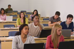 College students sitting at tiered desks in a lecture hall.