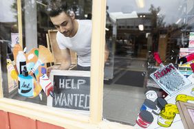 Male business owner placing Help Wanted sign in art supply shop window