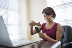 Businesswoman swiping credit card using reader