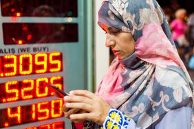 A woman checks her cell phone in front of currency exchange kiosk