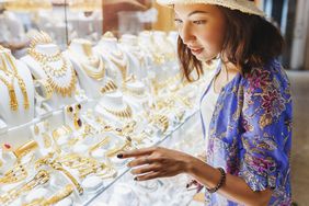 Woman looking at golden jewelry in a shop window