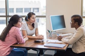 Loan officer talks with mother and daughter at a desk