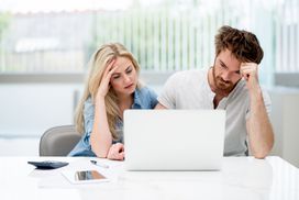 Man and woman worry in front of a laptop