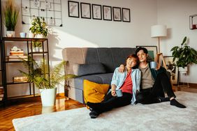 Young couple sitting on floor of apartment against sofa