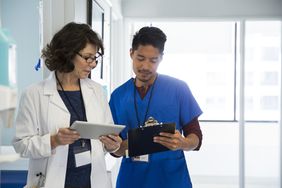A doctor and a nurse review information on a tablet device. 