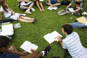a circle of college students studying outside on a grassy area