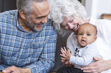 Grandparents smile at their infant grandchild. 