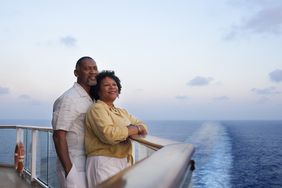 Couple on deck with cruise ship wake behind them