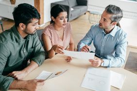 A male and female business couple meets with a lawyer to look over documents