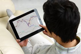 Man looking at stock market graph chart on digital tablet