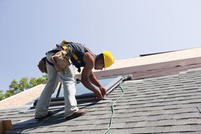 A construction worker repairs a roof.