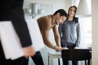 Woman looking at real estate agent while man signing documents at new home 