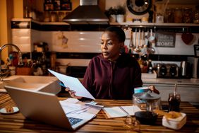 Young woman working on finances in kitchen in the evening