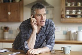  man in flannel shirt using phone in kitchen