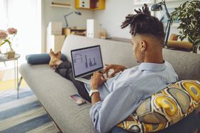 Young man working at laptop at home on his sofa
